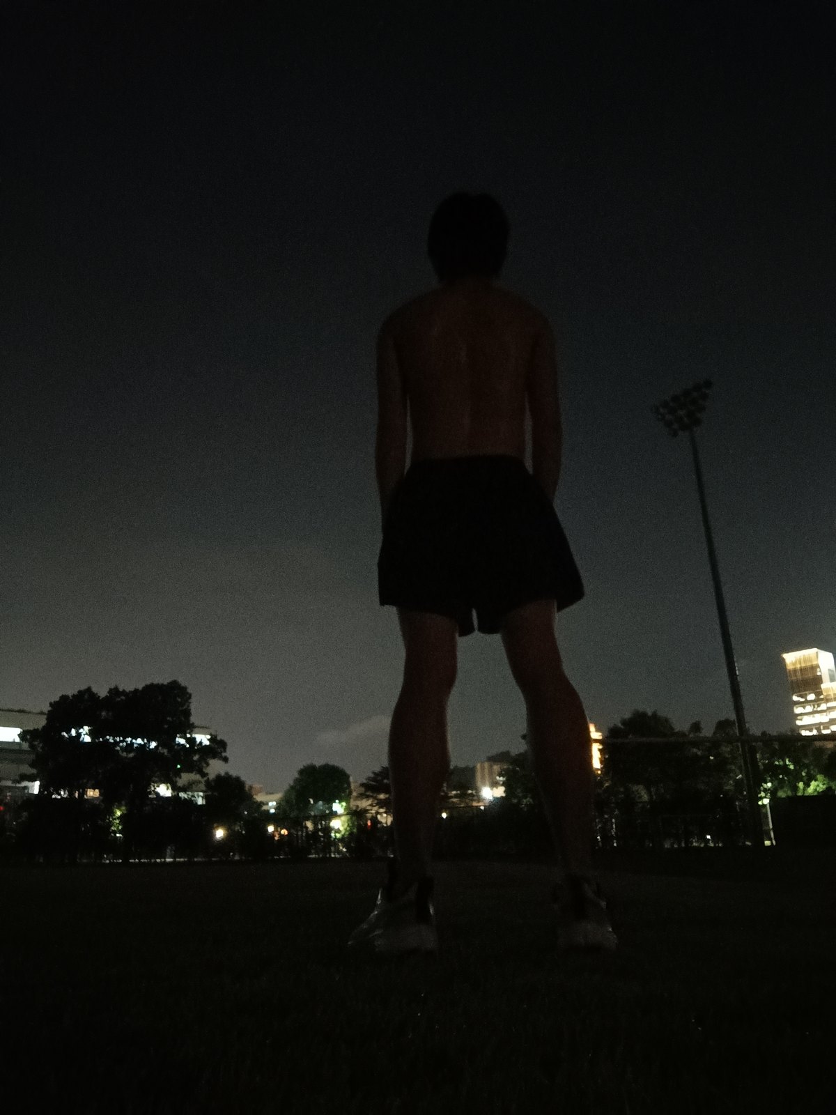背对镜头，站在夜色里